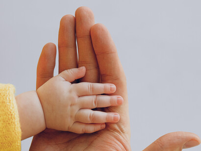 Mãos se encontram e afetos são trocados entre mãozinha de filho e pai