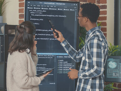 Database admin team reviewing source code on a large wall display as developers use AI for error detection