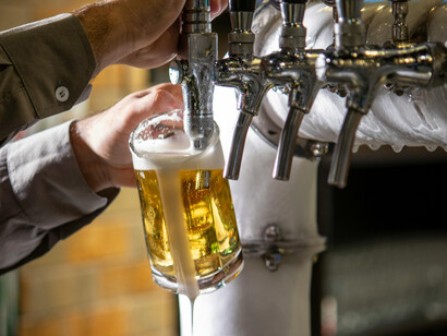 In a craft brewery, a man pours beer, capturing a step in the brewing process