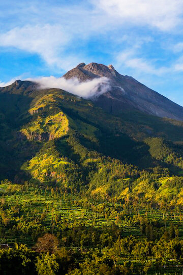 From the foot of Mount Merapi in Indonesia, the lush terrain and blue skies provide a perfect backdrop for adventurers and history buffs alike to explore the impact of the 2010 eruption