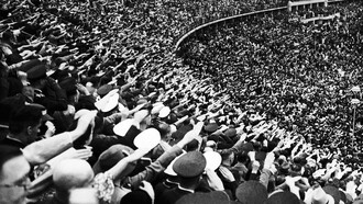 Una multitud en un estadio alemán hacen el saludo típico nazi (nacionalsocialista)
