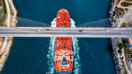 A large red tanker or chemical carrier passing beneath a modern cable-stayed bridge, Turkey