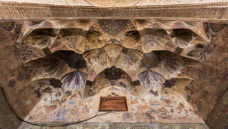 The vaulted ceiling at the entrance of the Ganjali Bathhouse, built in 1631 as part of a larger architectural complex in the old center of Kerman, Iran, features frescoes adorned with Safavid-era ornaments