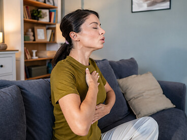 A woman practicing deep-breathing meditation at home, reflecting the connection between the mind, body, and emotional healing