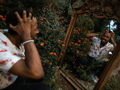 A man looks to himself in a mirror, with his hands on his head in frustration