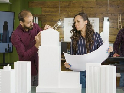 Architects analyzing a 3D-printed model of a commercial office building, integrating ideas of virtual construction sites, advanced 3D building modeling, and modern building management systems