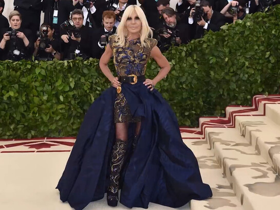 Donatella Versace in an intricately embellished ensemble, symbolizing the luxury and theatrical elegance of the Versace house
