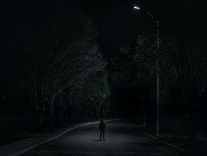 Ragazza che cammina nella notte in un luogo solitario sotto la luce di un unico lampione