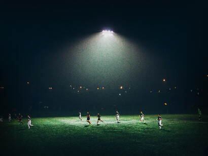 Faro de luz destaca por encima de un campo de fútbol mientras se juega un partido