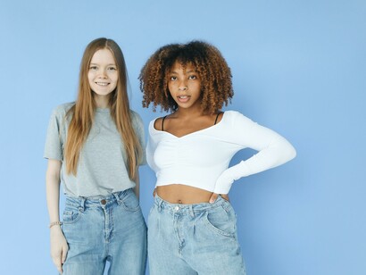 Two friends stood in a blue room looking at the camera 