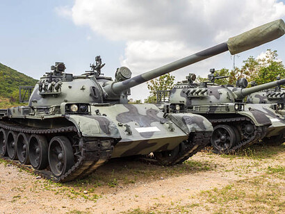 A row of heavy military tanks positioned on a training ground for inspection and readiness