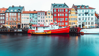 A charming scene unfolds in Copenhagen, Denmark, where a boat rests gently alongside a dock, exuding serene winter vibes