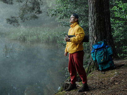 A young man besides a forest lake
