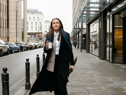 A woman in a black coat and scarf walking down the street