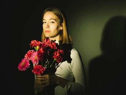 A contemplative woman holding a bouquet of flowers