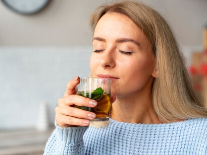 A woman drinks kombucha, savoring its refreshing taste