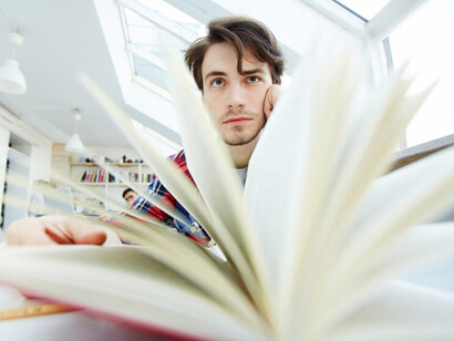 A student reading in the library, overwhelmed by academic stress, with OCD, sitting with their head in their hands