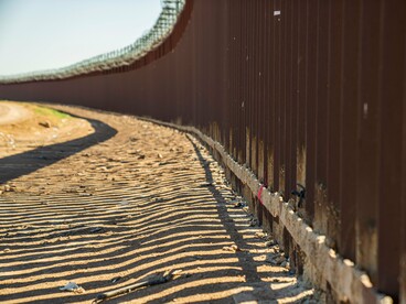 A weathered border barrier under the afternoon sun, reflecting the tightening of immigration policies across the region
