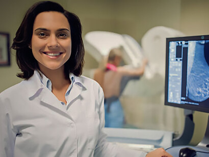 A female doctor smiles as she shakes hands with her Hispanic patient following a consultation in her office