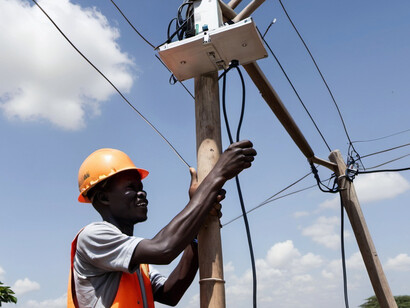 An electrician secures cables to an internet pole, part of a wider initiative to improve connectivity in remote African villages