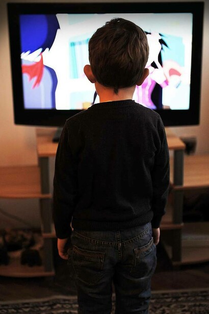 Bimbo in piedi davanti alla TV: “Ogni momento di esposizione alla TV prima dei 2 anni si traduce in una riduzione delle interazioni verbali tra genitori e figli”