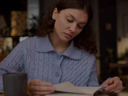Woman enjoying a peaceful moment in a cafe, reading a book and drinking tea