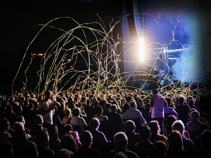 A closeup of the audience of the concert shows the light streamers showering down on them