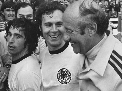 Beckenbauer (al centro) festeggia la vittoria del Mondiale 1974 con Gerd Müller (a sinistra) ed Helmut Schön (a destra)