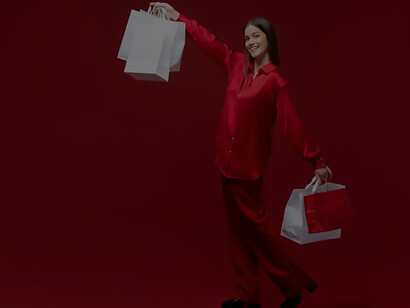 A jubilant woman beams with joy while showcasing her colorful shopping bags in a full-frame shot