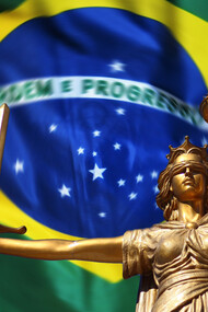 Statue of justice in front of the flag of Brazil