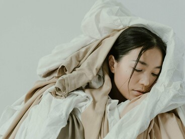 Mulher cercada de peças de roupa. Com o tempo e a evolução da indústria, o mercado precisou se adaptar a uma nova realidade e aos novos hábitos de consumo. E onde entra a sustentabilidade nisso? Quando falamos de moda, o meio ambiente precisa ser levado em consideração