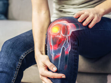 An older woman gently supports her knee at home, reflecting the daily impact of arthritis and knee pain
