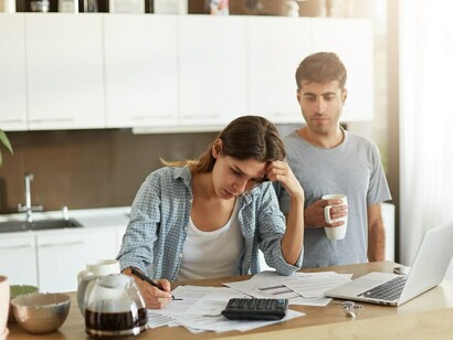 A young couple analyzing their family budget while managing the stress of financial uncertainty and work challenges