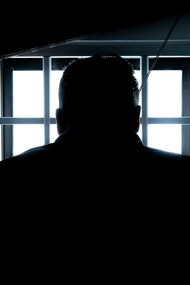 A person sat alone looking towards a window