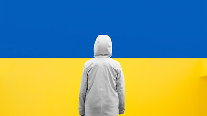 A child standing in front of a blue and yellow wall, Ukrainian flag colors