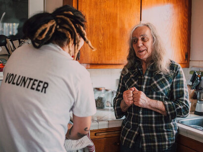 A volunteer assisting an elderly person with house cleaning, spreading kindness and support in the community