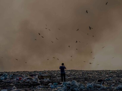 A photographer standing in a pile of garbage in the middle of a violent pollutant storm is no doubt a signal to call to fix the climate