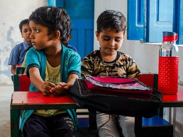 Children gathered in a simple classroom setting, representing the urgent need to make quality education accessible to every child