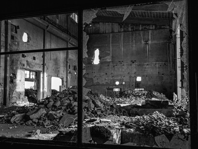 Paisaje de ruina industrial. Escombros acumulados y paredes con agujeros en un interior de hormigón y metal