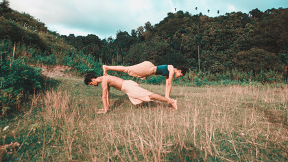 Casal de praticantes de yoga fazem uma posição desafiadora 