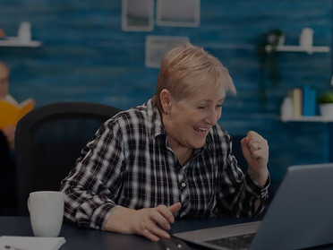 Joyful elderly woman happily performing computer tasks