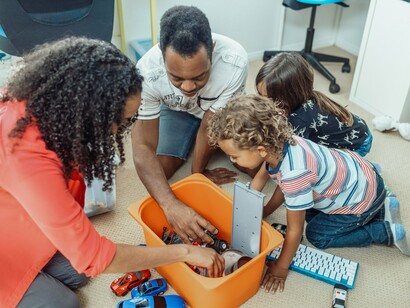 Uma família se reúne para brincar em casa, compartilhando um momento de diversão entre gerações. O fascínio pelos brinquedos atravessa o tempo e ajuda a construir lembranças que permanecem vivas na vida adulta