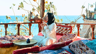 A visitor savouring tea amid traditional Moroccan décor overlooking the coast, reflecting how cultural experiences contribute to a country’s tourism identity