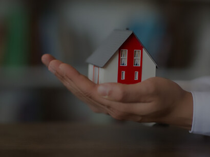 In the context of America's housing crisis and economic recession, a businessman holds a miniature house savings model, representing the challenges and aspirations amid the current real estate landscape