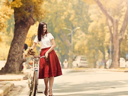 Una chica elegante pasea en bicicleta por el parque