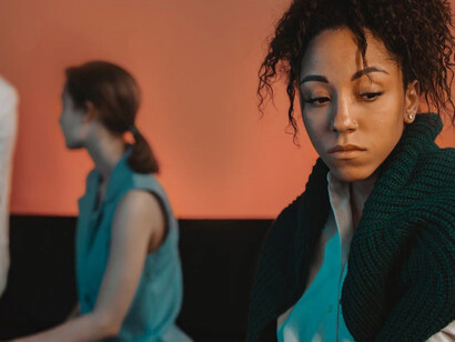 A solitary black woman, starkly set apart, stands before two white women