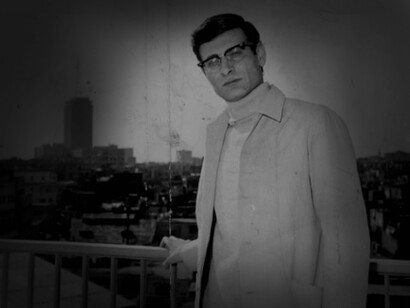 Mahmoud Darwish leaning on a balcony in a city in Palestine
