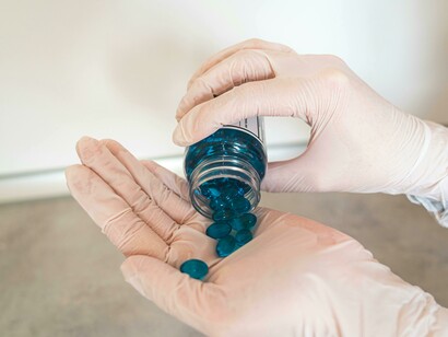 A close-up of a person's hand holding a blue pill, representing the link between modern medicine and DNA-based therapies