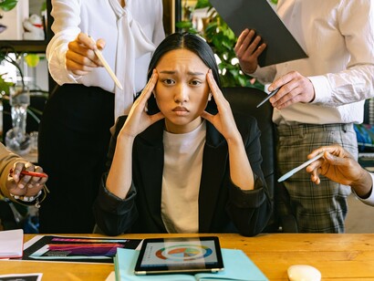 An employee receiving input from multiple coworkers at the same time, reflecting the demands of a collaborative workplace