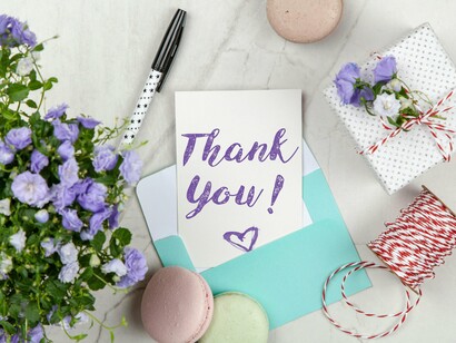 A handwritten thank-you card among flowers and small gifts, representing the power of expressed appreciation